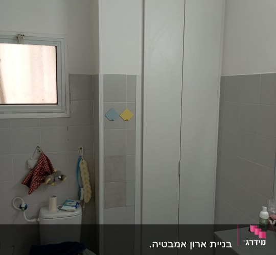 ארון עץ לבן עם דלתות סגורות בחדר אמבטיה